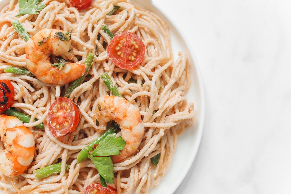 A plate of asparagus and shrimp pasta with lemon garnish