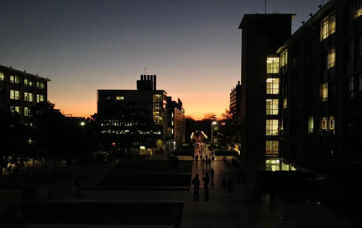 A college campus bathed in warm golden light at sunset, with students enjoying the peaceful atmosphere