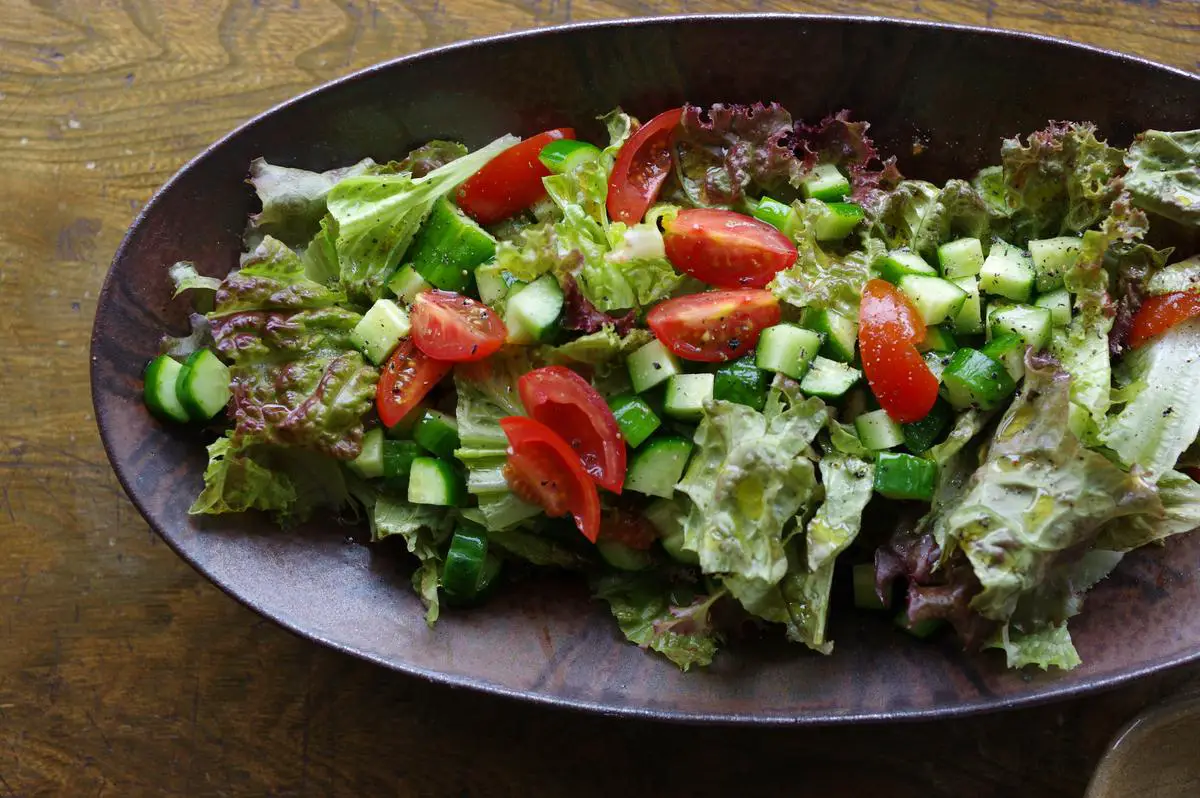 A vibrant Green Goddess Salad with fresh leafy greens, avocado, radishes, and cucumber slices