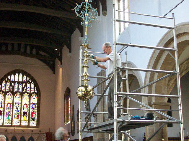 A person polishing a chandelier or decorative light fixture