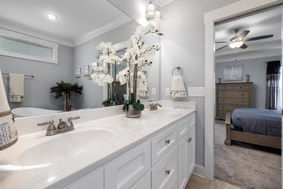 A clean and organized bathroom with clear storage containers and fresh flowers