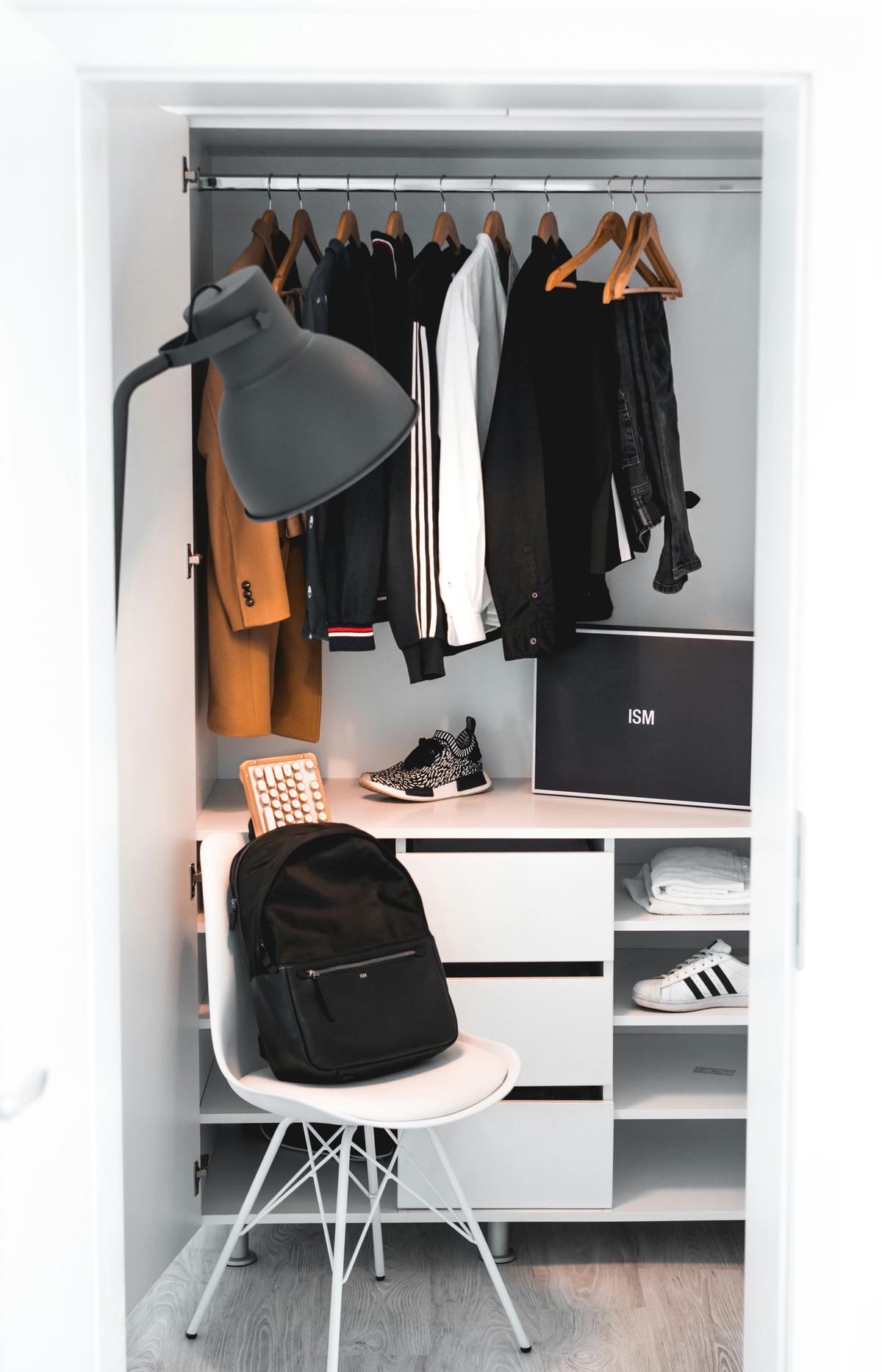 An open wardrobe showing a mix of winter and summer clothes being organized